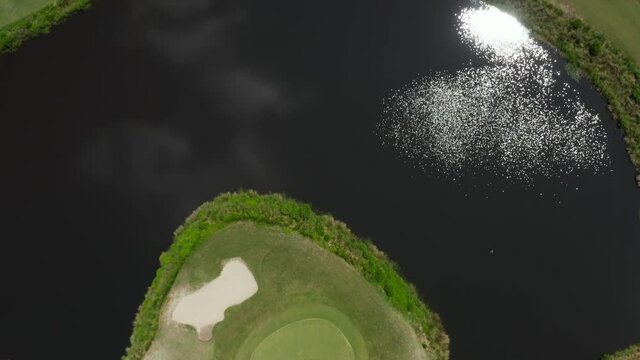 Golf course in low country, USA. Blackwater hazard, sand traps on course greens. Top down aerial drone shot.