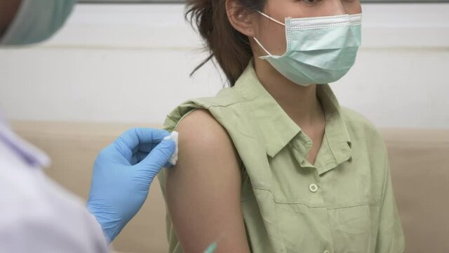 Vaccination, Doctor man injection coronavirus vaccine to young woman her shoulder, female patient in medical face mask, Covid-19 pandemic outbreak Medicine And Health Care Concept