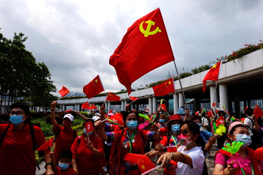 Pro-China supporters hold Chinese and Communist Party of China flags to celebrate the 24th anniversary of the former British colony's return to Chinese rule, on the 100th founding anniversary of the Communist Party of China, in Hong Kong