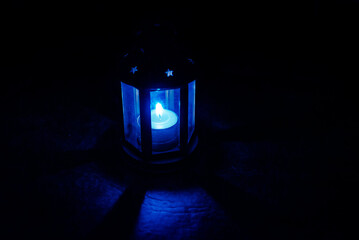 Spooky magic candle lamp with star shaped holes shining from inside. Lighting dimly the floor and...