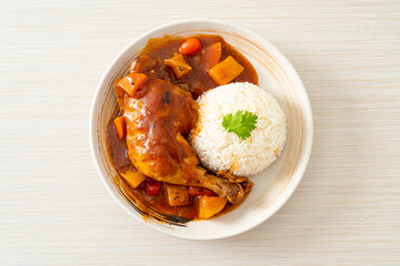 chicken stew with tomatoes, onions, carrot and potatoes on plate with rice