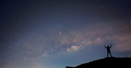 Obraz premium Milky Way. Night sky with stars and silhouette of a standing happy man with yellow light with noise and grain.Photo by long exposure and select white balance.selection focus.amazing. Space background
