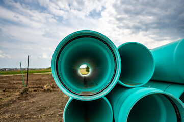 Stacked water main pipe with bell fitting next to an exposed trench for installation