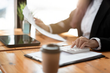 accountant working on desk using calculator for calculate finance report in cafe shop.