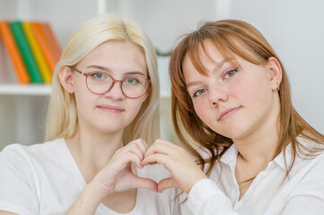 Two smiling young girl show one heart sign. LGBT concept