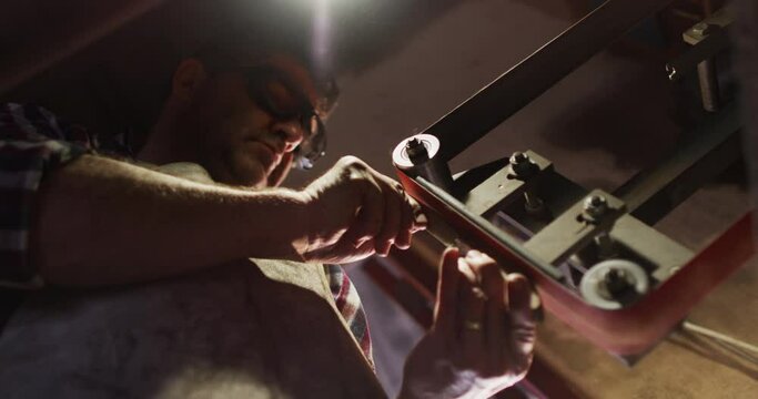 Close up of caucasian male knife maker in workshop holding knife and using sander