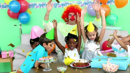 Animation of gold confetti over diverse happy children and clown having fun at party - Powered by Adobe