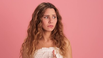 An excited woman fingering her fingers and grabbing her head in a pink studio
