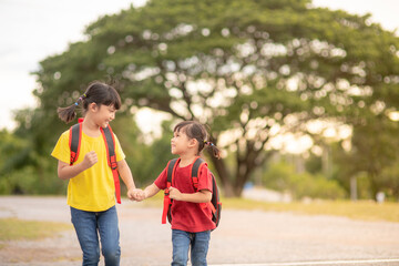Cute Asian children holding hand together while going to the school