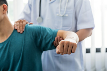 Man physiotherapist stretching shoulder and arm patient at a clinic.