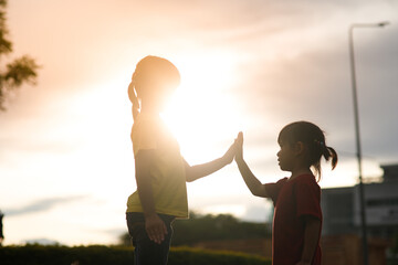 Cute asian child girl making hi five gesture and sunset