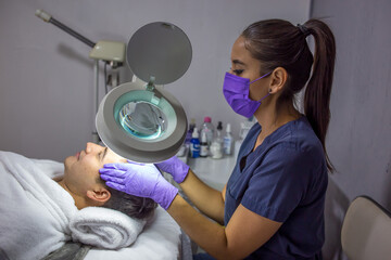 Cosmética masculina. Esteticista Hombre guapo recibiendo tratamiento facial en el spa