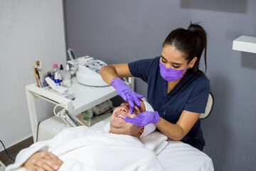 Cosmética masculina. Esteticista Hombre guapo recibiendo tratamiento facial en el spa