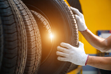Asian male tire changer In the process of checking the condition of new tires in stock so that they...
