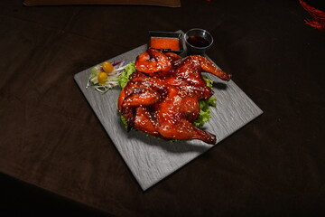 roasted bbq whole chicken in red honey sauce with sesame seed on top black stone plate