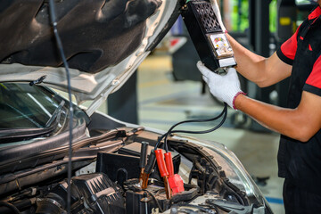 Close-up of an auto mechanic in a service center checking battery polarity and checking electrical...