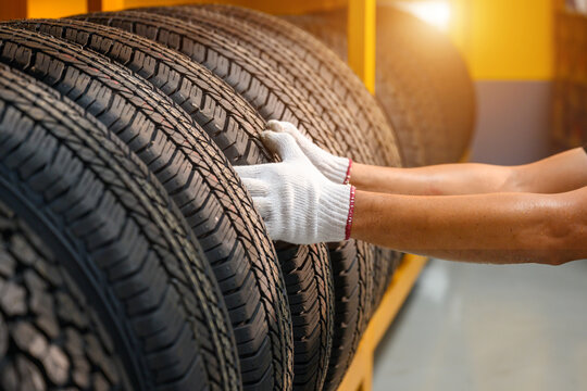 Asian male tire changer In the process of checking the condition of new tires in stock so that they can be replaced at a service center or auto repair shop. Tire warehouse for the car industry