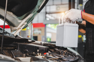 Close-up of a car mechanic in a service center picking up a new battery to replace the car. for cars that use the service Replace the battery at the store