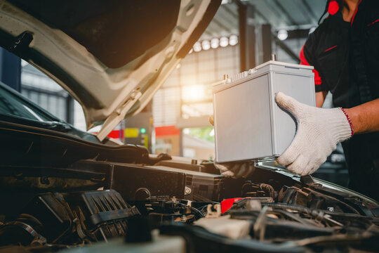 Close-up of a car mechanic in a service center picking up a new battery to replace the car. for cars that use the service Replace the battery at the store