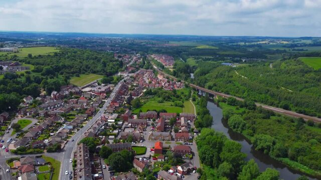 Tilting down from an aerial view of Conisbrough with train bridge and River Don.