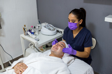 Cosmética masculina. Esteticista Hombre guapo recibiendo tratamiento facial en el spa