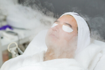 Cosmética masculina. Esteticista Hombre guapo recibiendo tratamiento facial en el spa