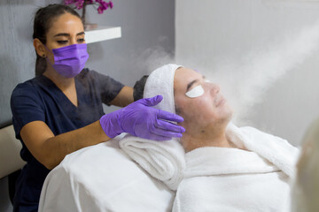 Cosmética masculina. Esteticista Hombre guapo recibiendo tratamiento facial en el spa