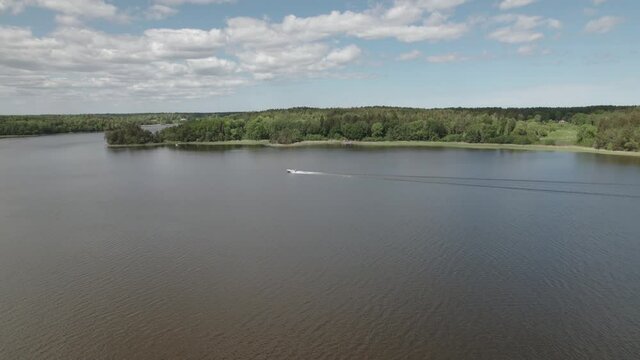 Drone approaching far away motor boat, in a Scandinavian lake, Sweden