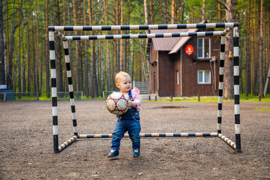 little active girl baby blond playing with football ball in the forest, Siberia, Russia