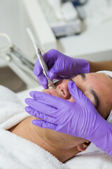Cosmética masculina. Esteticista Hombre guapo recibiendo tratamiento facial en el spa