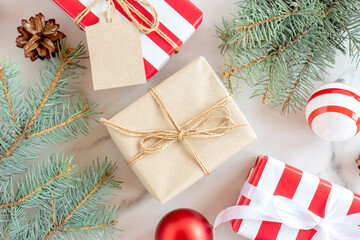 Christmas and New Year background with conifer branch, decorations and present wrapped in craft paper with baubles. Flat lay, top view.