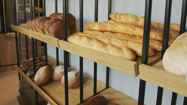 Tracking slowmo shot of fresh loaves of bread lying on shelves in bakery