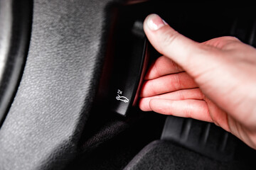Women's hand opens car hood unlock switch.