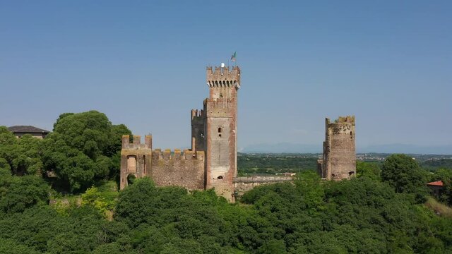 Aerial view of the Italian historic castle Castello Scaligero on a hill, view of the Ponte Visconteo bridge and the Mincio river. Italy flag at Scaligero castle.