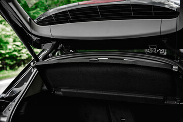 Fototapeta na wymiar Modern black car with open trunk door on road.