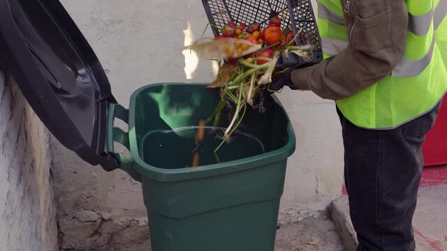 Food Waste at Retail. A supermarket worker or farmer throws spoiled rotten unsold vegetables into a dumpster. Food Waste and loss. Food throwing
