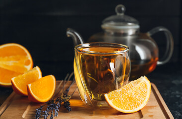 Glass of hot citrus tea on dark background