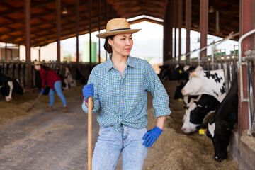 Emotional woman farm worker engaged in livestock breeding taking care of cows