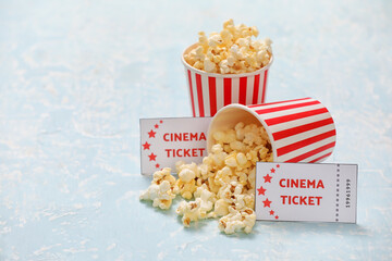 Buckets with tasty popcorn and cinema tickets on color background