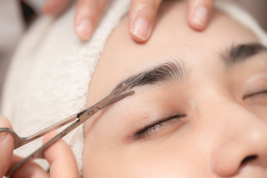 Eyebrows trimming service in spa salon, Face hair cutting and trim with small scissor tool for facial beauty women closeup.