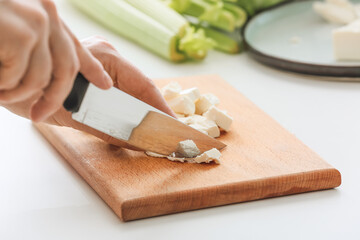 Woman preparing tasty salad with feta cheese on light table, closeup