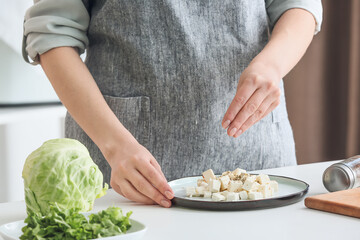 Obraz na płótnie Canvas Woman adding spices onto feta cheese on plate, closeup