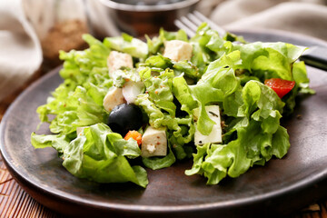 Wooden plate with fresh Greek salad on wooden background, closeup