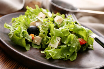 Plate with fresh Greek salad on wooden background, closeup