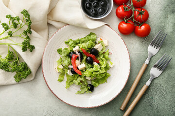 Plate with fresh Greek salad and ingredients on grunge background