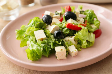 Plate with fresh Greek salad on color background, closeup