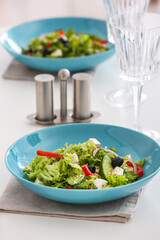 Plates with fresh Greek salad and glasses on table in restaurant