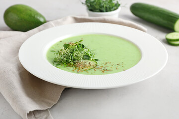 Plate with green gazpacho on light background