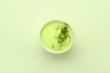 Bowl with green gazpacho on color background
