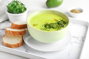 Tray with green gazpacho and ingredients on light background